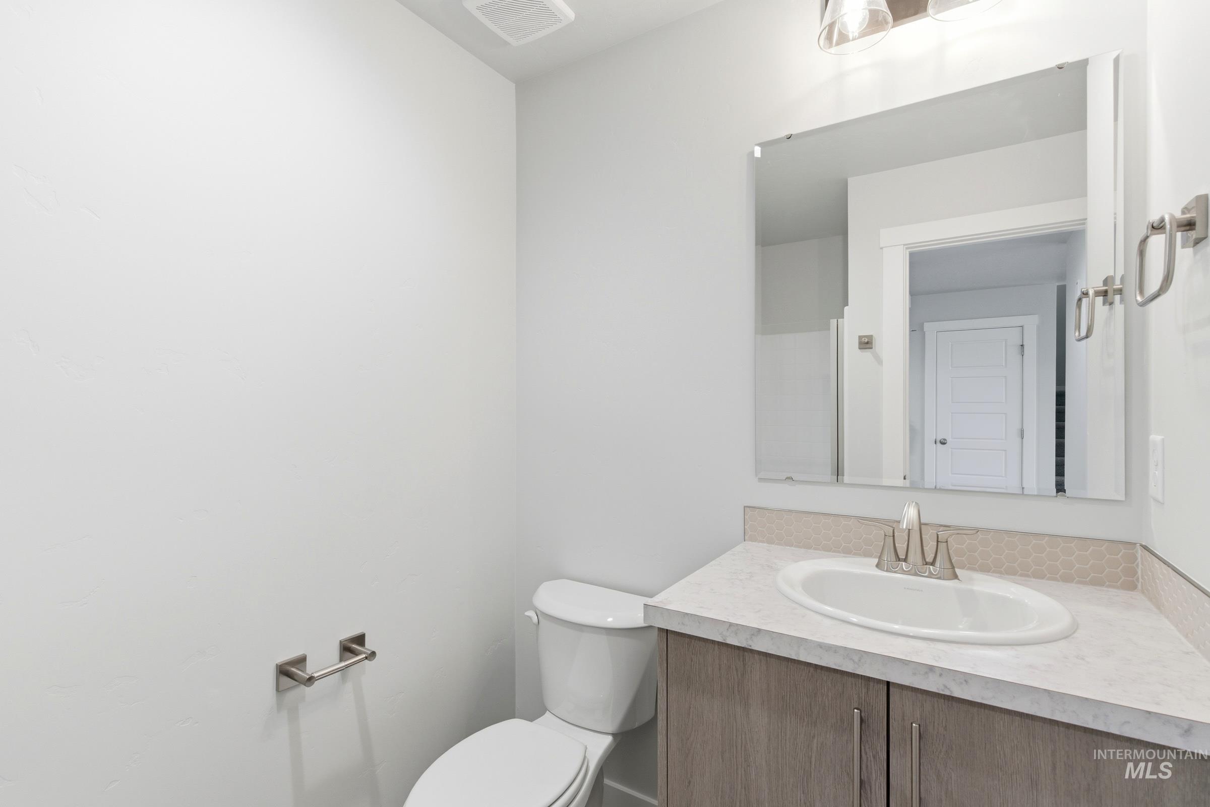 12829 Decatur Street Nampa, ID 83651 - Photo 14 of 33 Bathroom featuring a single vanity with wood-finish cabinetry, a white countertop, and a hexagonal tile backsplash