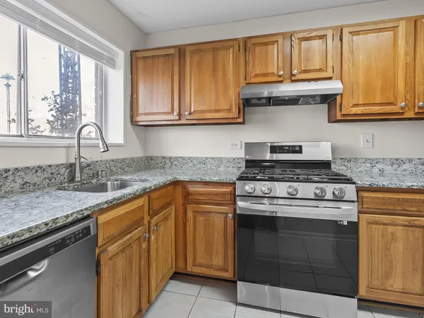 a kitchen with granite countertop stainless steel appliances white cabinets sink and window
