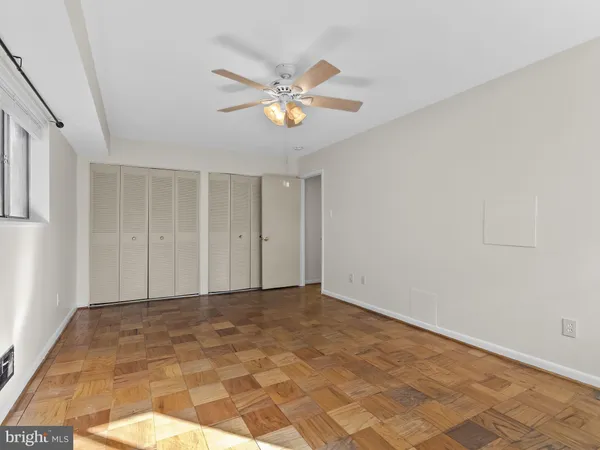 a view of an empty room with window and chandelier fan