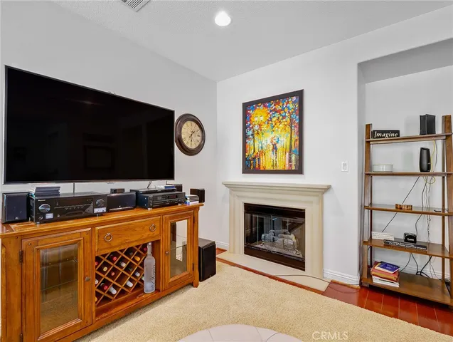 a living room with stainless steel appliances furniture a fireplace and a flat screen tv