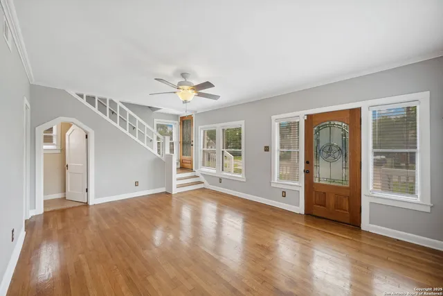 a view of an empty room with a window and wooden floor