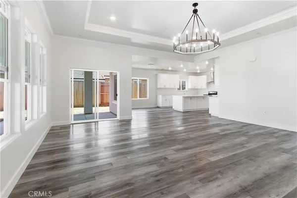 a view of a dining room with wooden floor chandelier and kitchen view