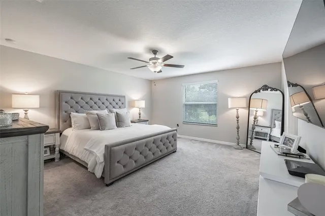 a spacious bedroom with a bed a chandelier and dresser