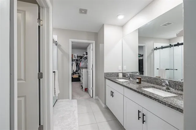 a en suite bathroom with a granite countertop sink and mirror