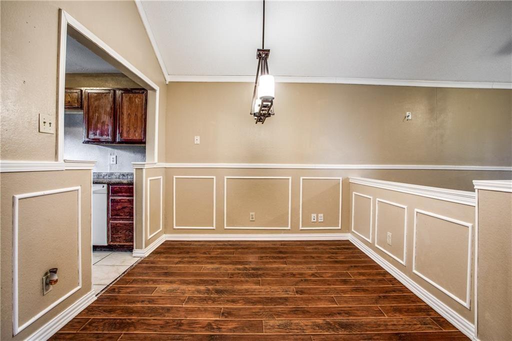 6817 Haltom Road Fort Worth, TX 76137 - Photo 15 of 25 Dining area featuring wood-finish flooring, wainscoting, crown molding, and a decorative chandelier
