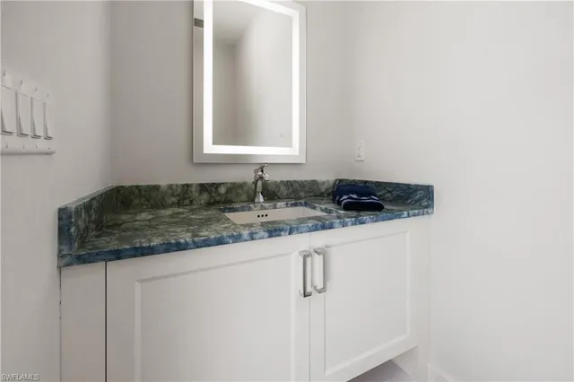 a bathroom with a granite countertop sink and a mirror