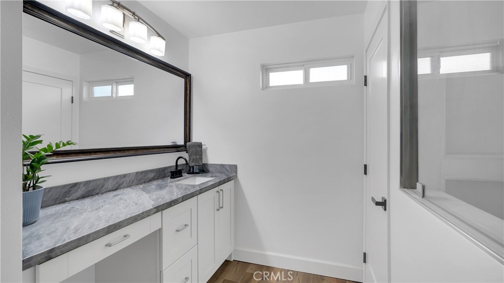 16281 Golden Gate Lane Huntington Beach, CA 92649 - Photo 16 of 22 a bathroom with a granite countertop sink a mirror and a shower