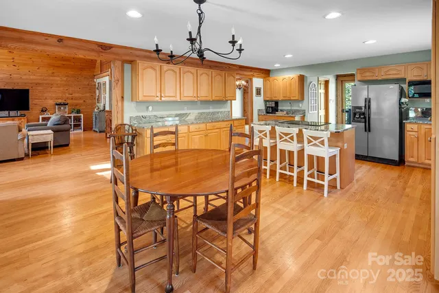 a dining room with stainless steel appliances kitchen island granite countertop a table chairs and a refrigerator