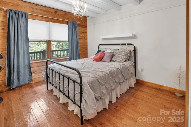 a bedroom with a bed and a large window with wooden floor