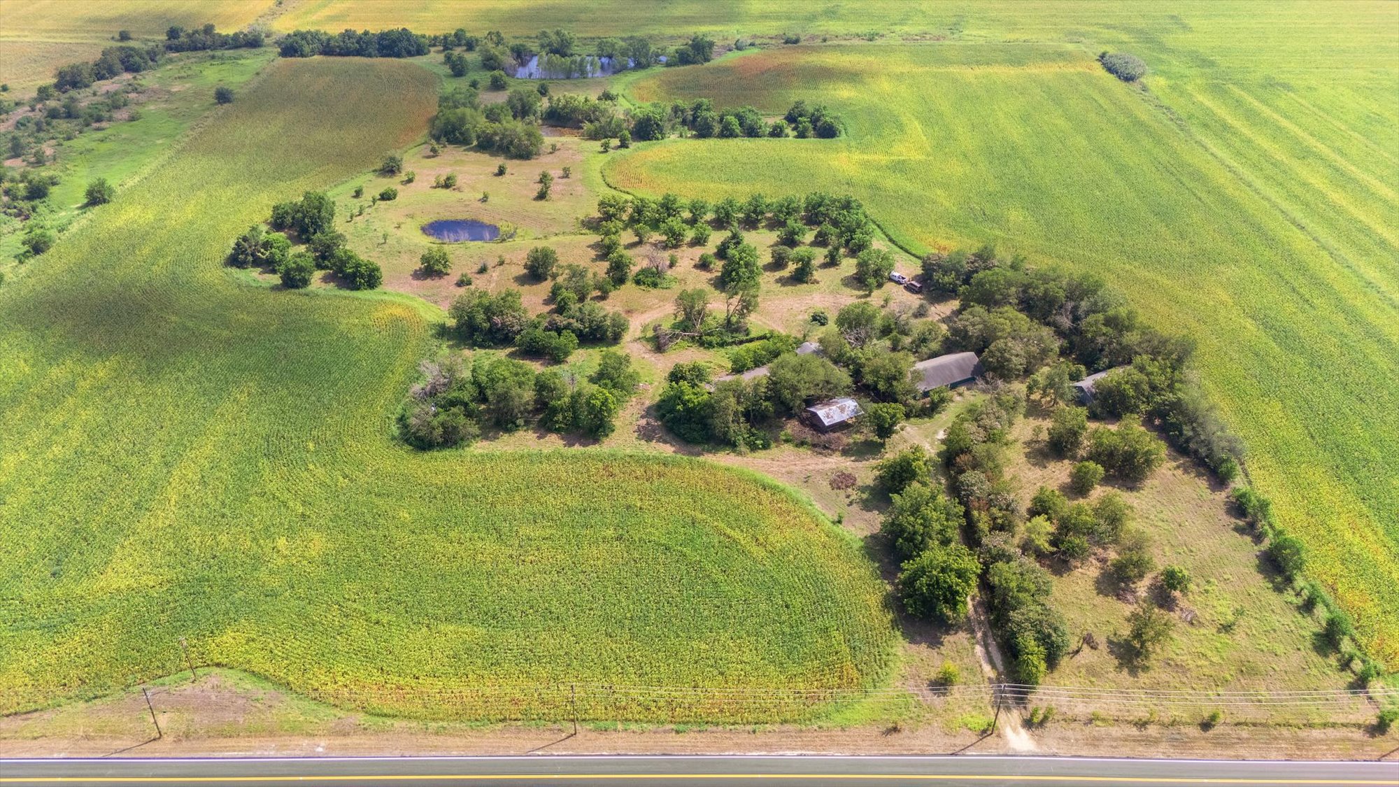 14201 Lund - Carlson Road Coupland, TX 78615 - Photo 27 of 40 An aerial perspective reveals a vast landscape of agricultural fields, dotted with mature trees and tranquil ponds, offering a serene rural escape.