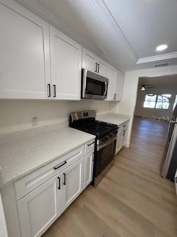 a kitchen with cabinets stainless steel appliances and wooden floor