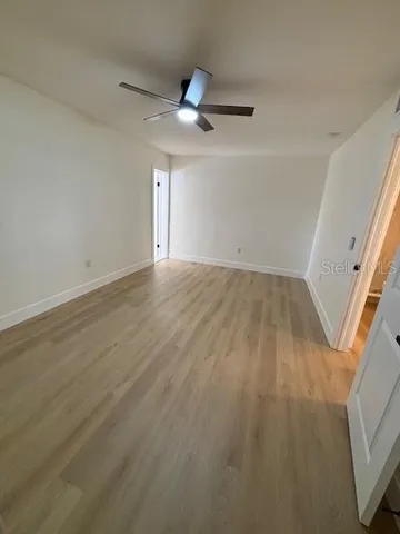 an empty room with wooden floor fan and windows