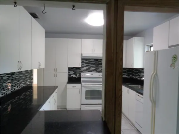 a kitchen with white cabinets and appliances