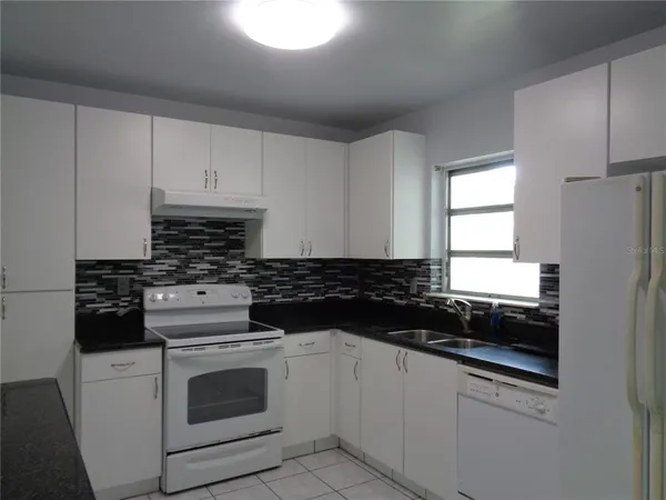 a kitchen with white cabinets and appliances