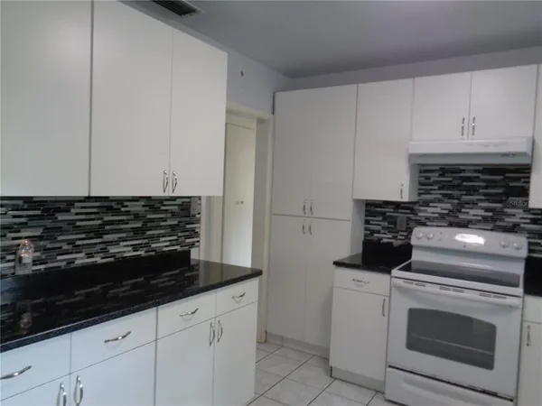 a kitchen with granite countertop white cabinets and stainless steel appliances