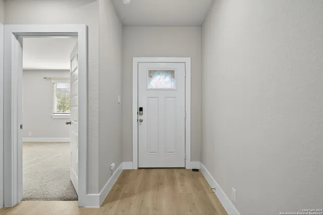 an empty room with wooden floor ceiling fan and windows