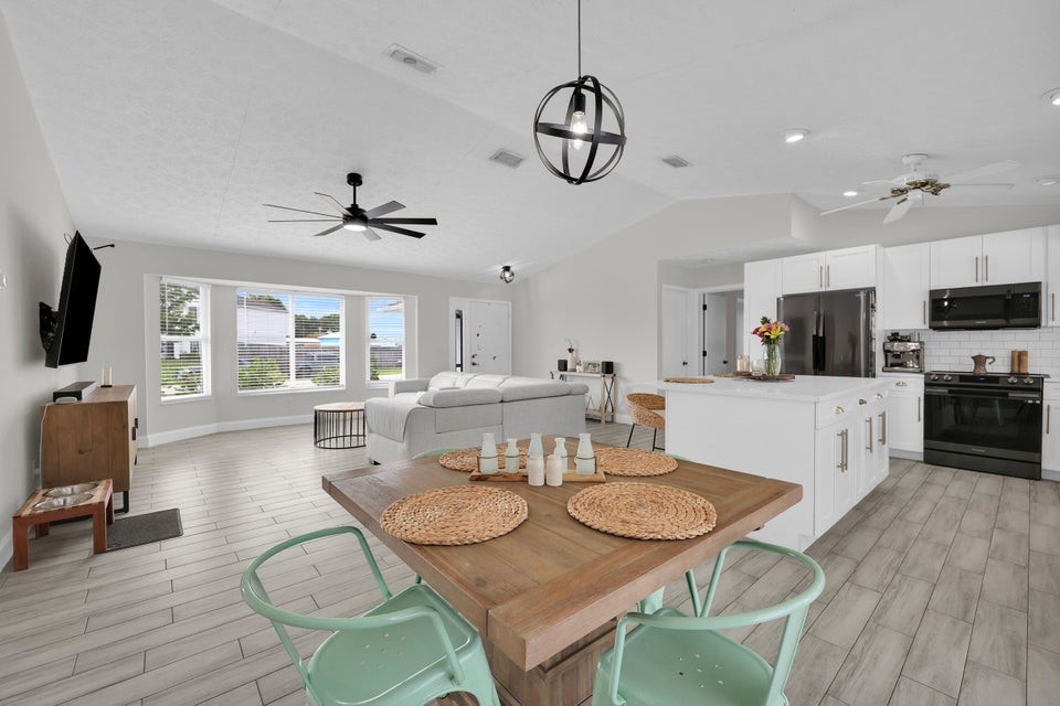 1950 Southwest Logwood Road Port St. Lucie, FL 34953 - Photo 13 of 32 a living room with furniture a flat screen tv and kitchen view