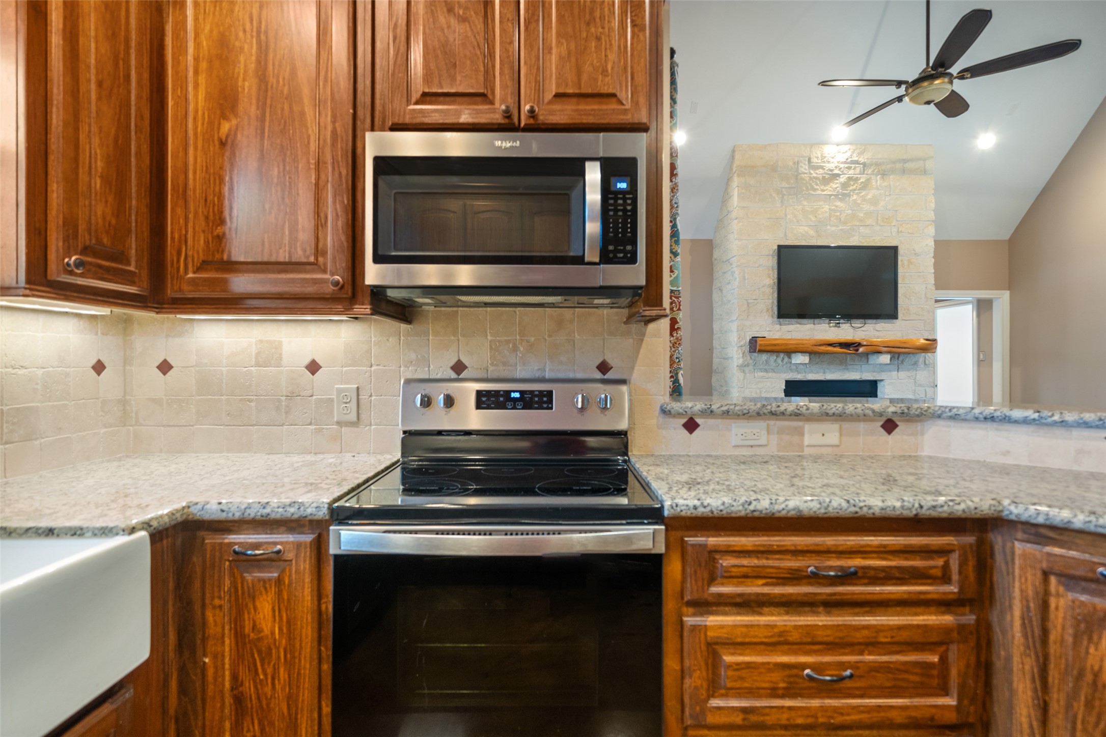 26752 Nelson Road Hempstead, TX 77445 - Photo 18 of 45 The kitchen features granite countertops, travertine tile backsplash, stainless range and microwave, and wood cabinetry, all set on polished concrete flooring.