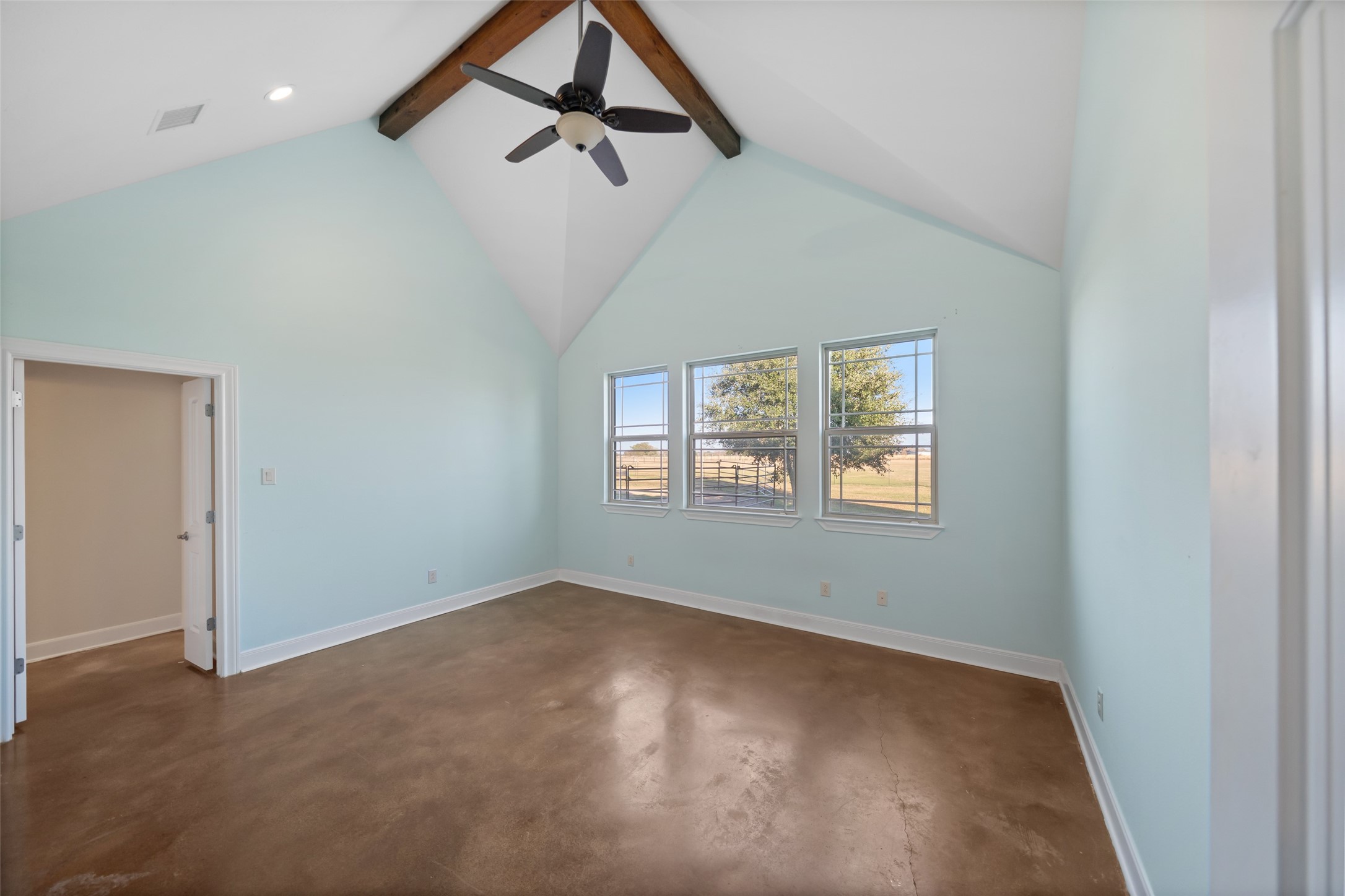 26752 Nelson Road Hempstead, TX 77445 - Photo 20 of 45 Primary bedroom features vaulted ceilings with exposed wood beams, ceiling fan, polished concrete flooring, and multiple windows with pasture views.