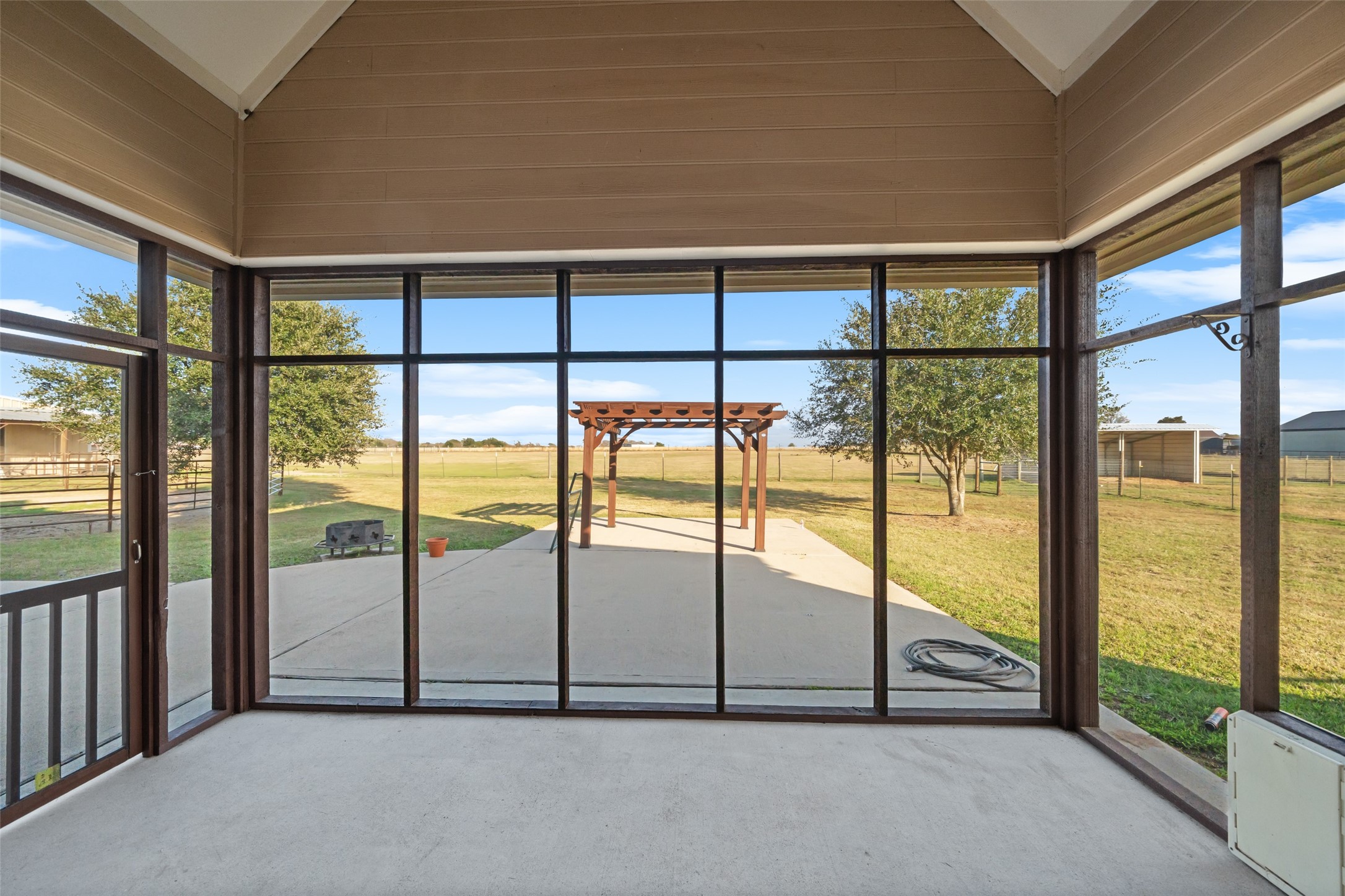 26752 Nelson Road Hempstead, TX 77445 - Photo 25 of 45 Large screened-in back porch provides a shaded outdoor living area with views of the patio, pergola, and surrounding pasture.