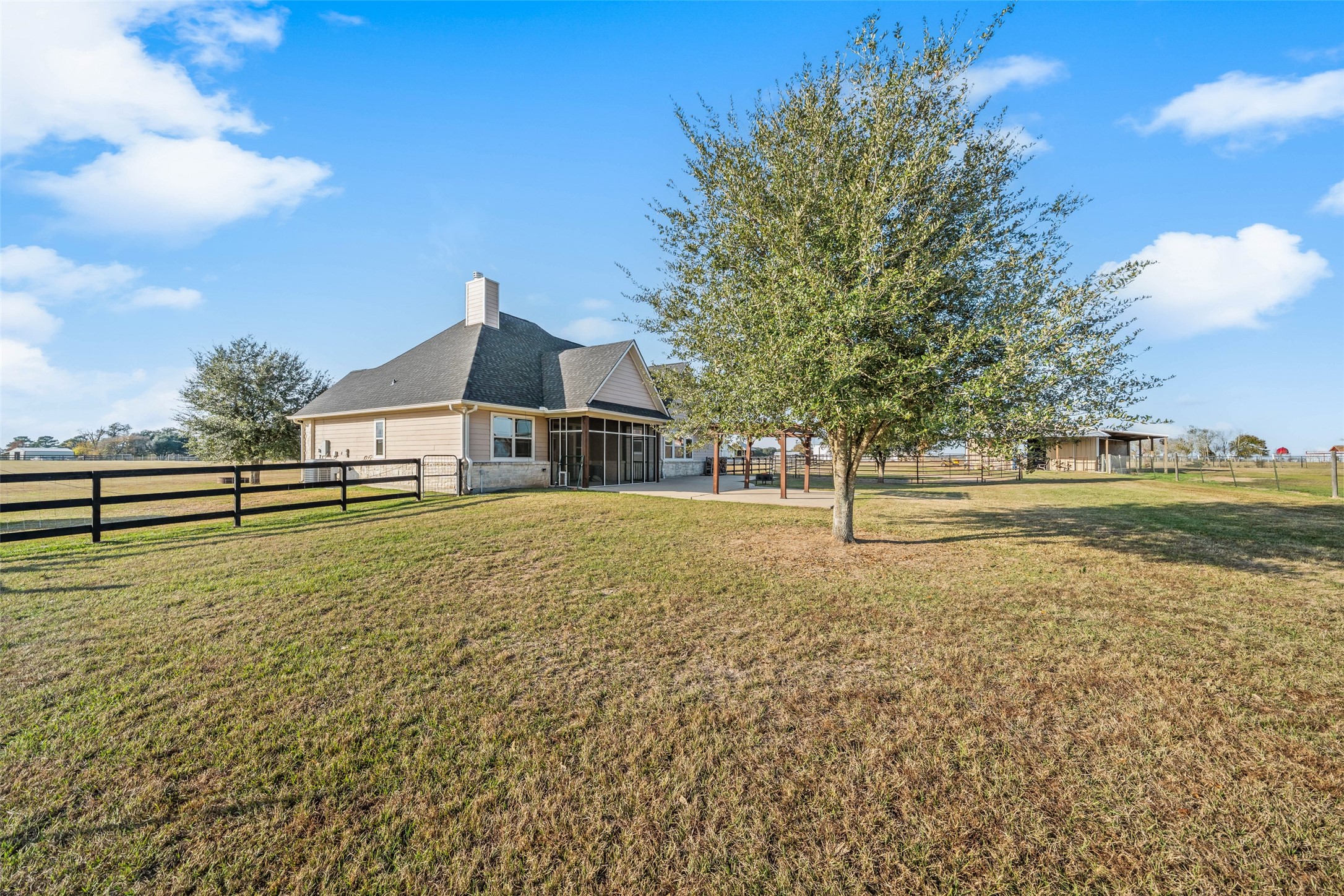 26752 Nelson Road Hempstead, TX 77445 - Photo 35 of 45 Rear view of the home showcases the screened porch, pergola-covered patio, mature shade tree, and expansive fenced yard.