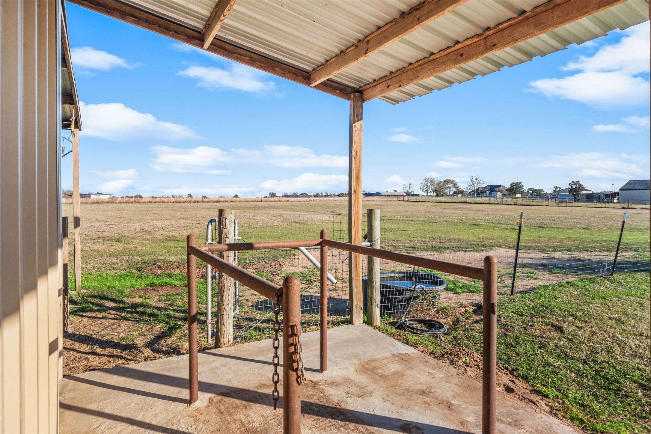 26752 Nelson Road Hempstead, TX 77445 - Photo 40 of 45 Covered concrete pad at the barn provides a practical space for feeding, grooming, or equipment access, with nearby fencing and pasture views.