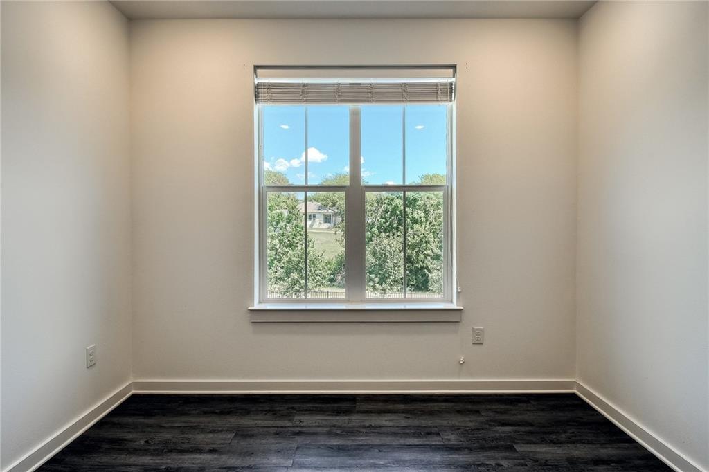 2624 Metcalfe Road, Unit 7 Austin, TX 78741 - Photo 22 of 31 Room featuring wood-finish flooring, a double-hung window with blinds, and light-toned wall paint with white trim