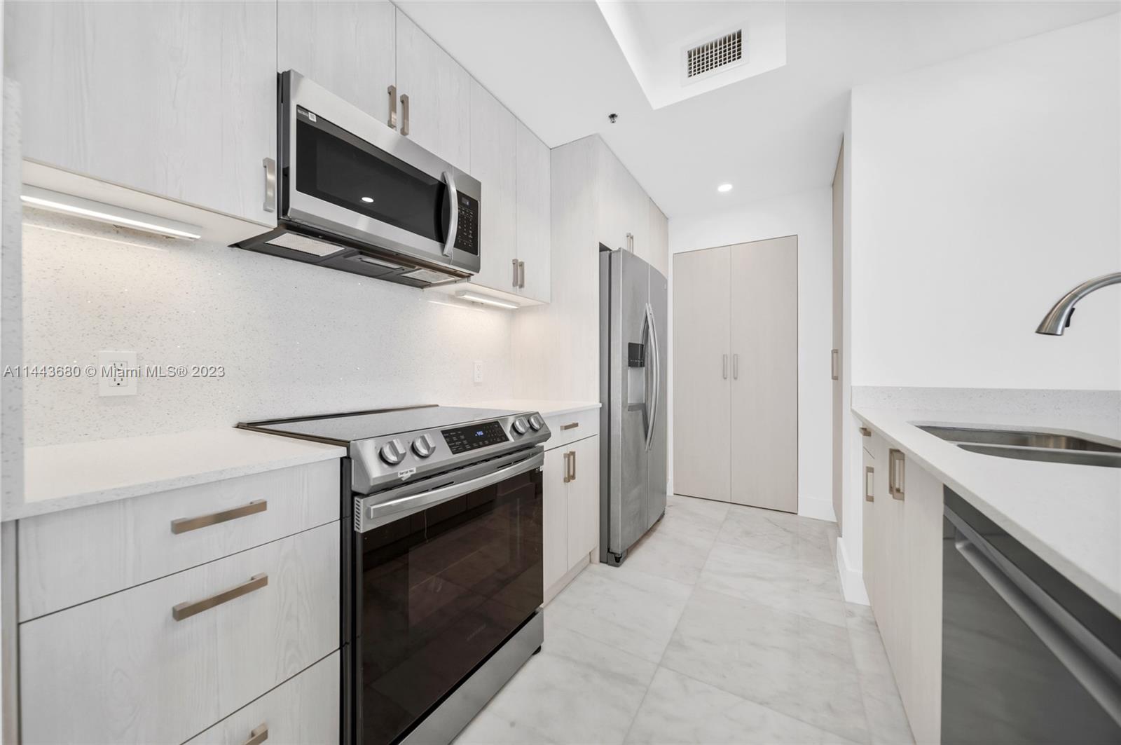 Brickell Key Miami, FL 33131 - Photo 9 of 40 a kitchen with stainless steel appliances white cabinets and a stove top oven