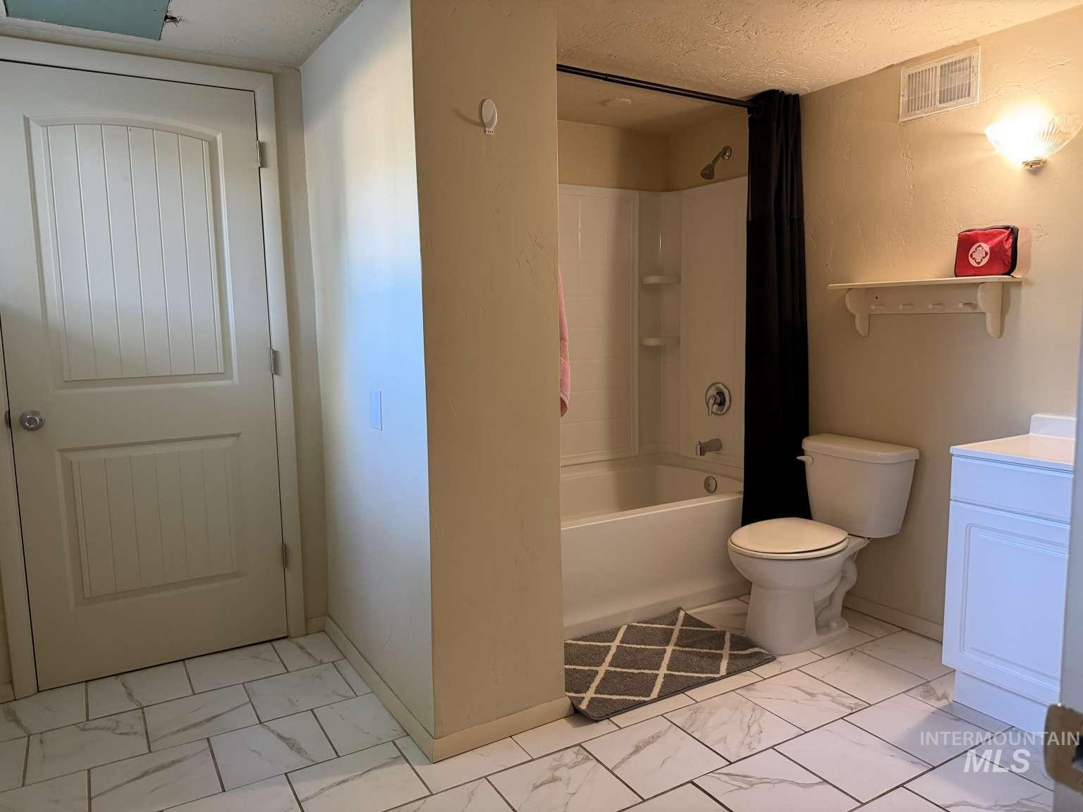 1158 South Powerline Road Nampa, ID 83686 - Photo 46 of 46 Bathroom featuring white tile flooring, a white vanity with a white countertop, and a white tub/shower combination with integrated shelving