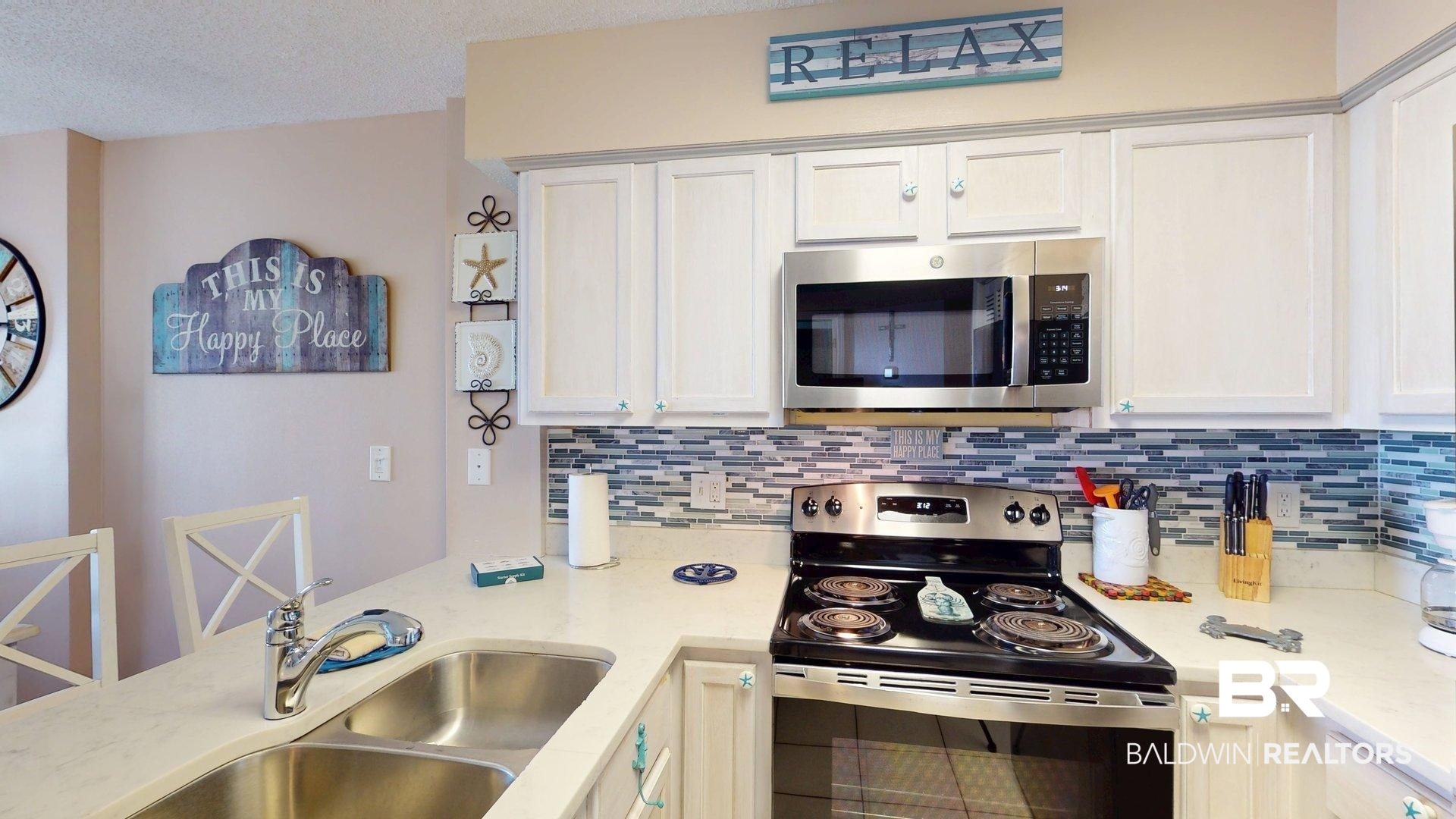 645 Plantation Road, Unit 6503 Gulf Shores, AL 36542 - Photo 26 of 53 Kitchen with appliances with stainless steel finishes, backsplash, white cabinets, light stone countertops, and a textured ceiling