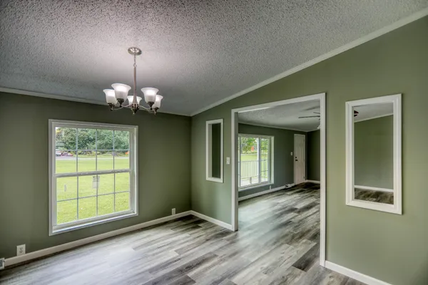 an empty room with a chandelier fan and windows