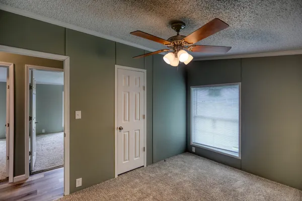 an empty room with a chandelier fan and windows