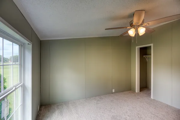 an empty room with windows and ceiling fan