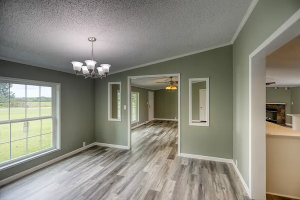 a view of an empty room with a chandelier fan