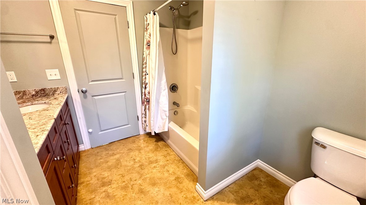 2603 Rockefeller Road Wickliffe, OH 44092 - Photo 23 of 34 Bathroom featuring a vanity with a light-toned stone countertop, an integrated sink, dark wood-finish cabinetry, and a combination shower-tub unit
