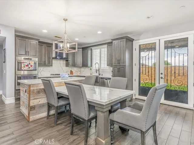 a dining room with stainless steel appliances furniture a chandelier and a view of kitchen