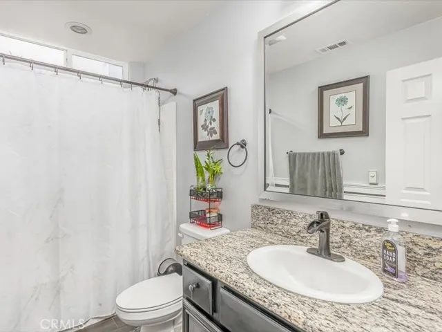 a bathroom with a granite countertop sink toilet a mirror and a shower