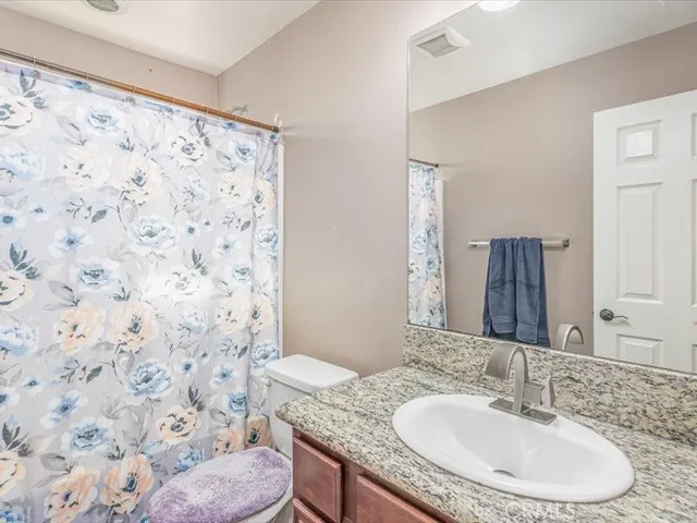 a bathroom with a granite countertop sink a toilet and a mirror