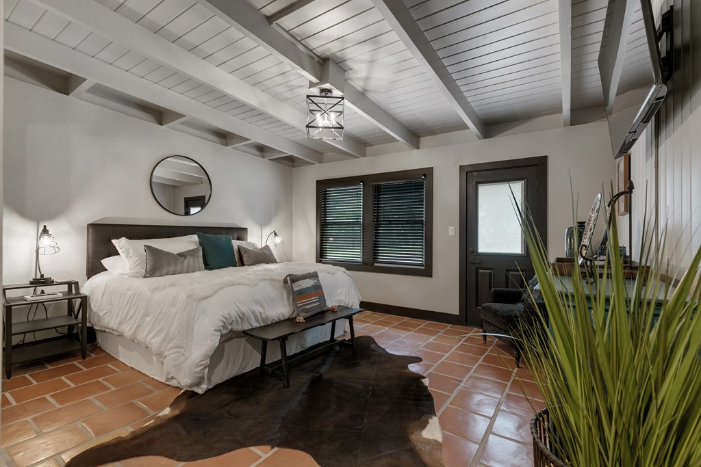 48 Kneese Road Fredericksburg, TX 78624 - Photo 13 of 43 a bedroom with a large bed and a chandelier