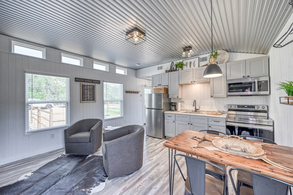 48 Kneese Road Fredericksburg, TX 78624 - Photo 31 of 43 a kitchen with stainless steel appliances granite countertop a stove a refrigerator a sink dishwasher a dining table and chairs with wooden floor