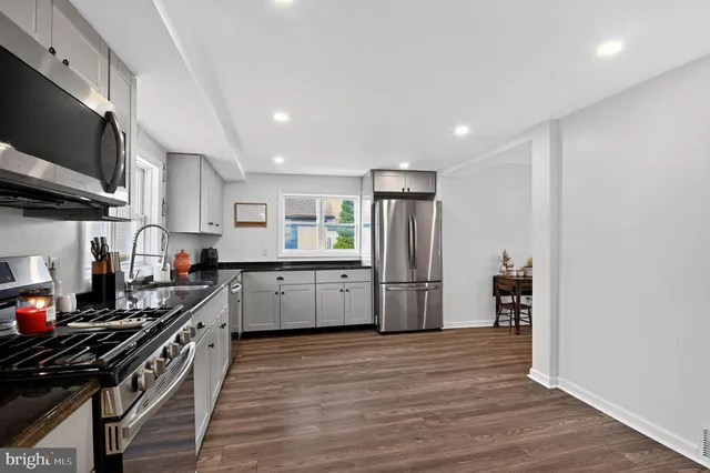 a kitchen with stainless steel appliances a refrigerator a stove a microwave and wooden floor