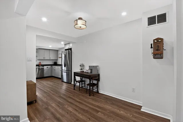 a kitchen with stainless steel appliances wooden floor and chairs