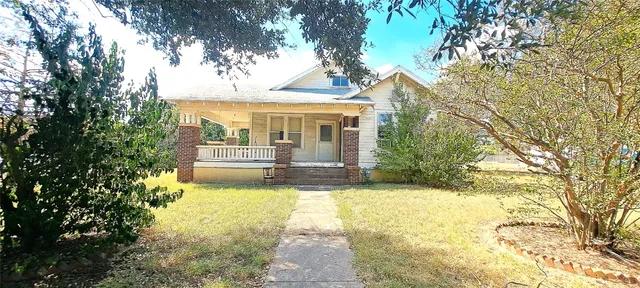a view of a house with a large tree and a yard