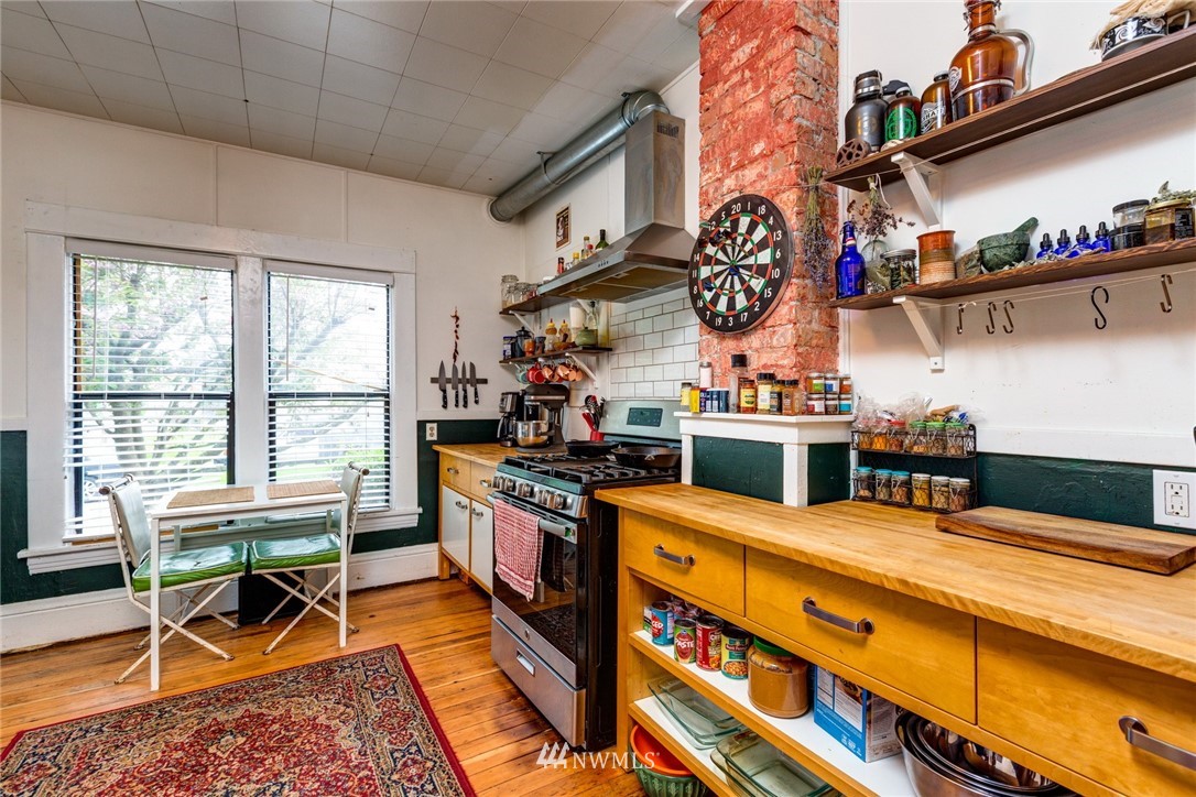 1717 Monroe Street Bellingham, WA 98225 - Photo 13 of 37 a kitchen with stainless steel appliances granite countertop a stove a refrigerator a dining table and chairs with wooden floor
