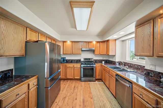 a kitchen with stainless steel appliances granite countertop a refrigerator a sink dishwasher a stove with wooden floor and cabinets