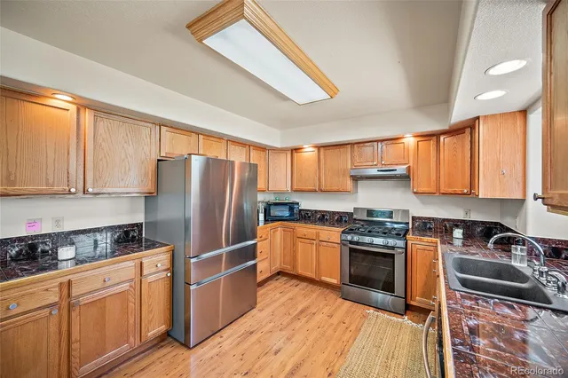 a kitchen with stainless steel appliances granite countertop a refrigerator stove top oven and sink
