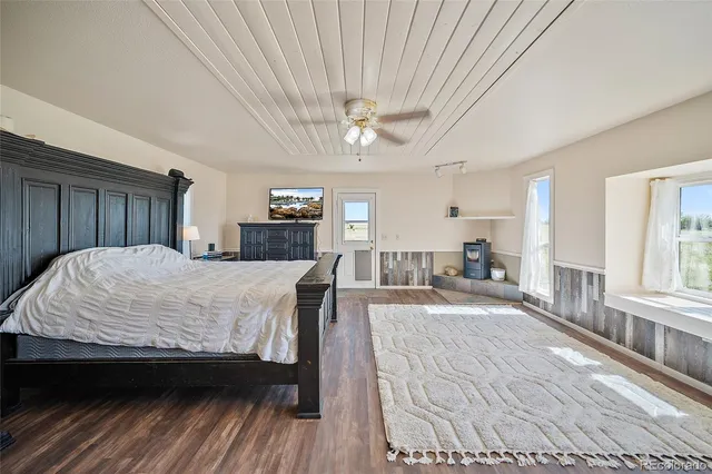 a spacious bedroom with a large bed a chandelier and windows