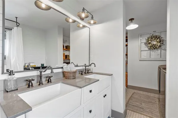 a bathroom with a double vanity sink mirror and bathtub