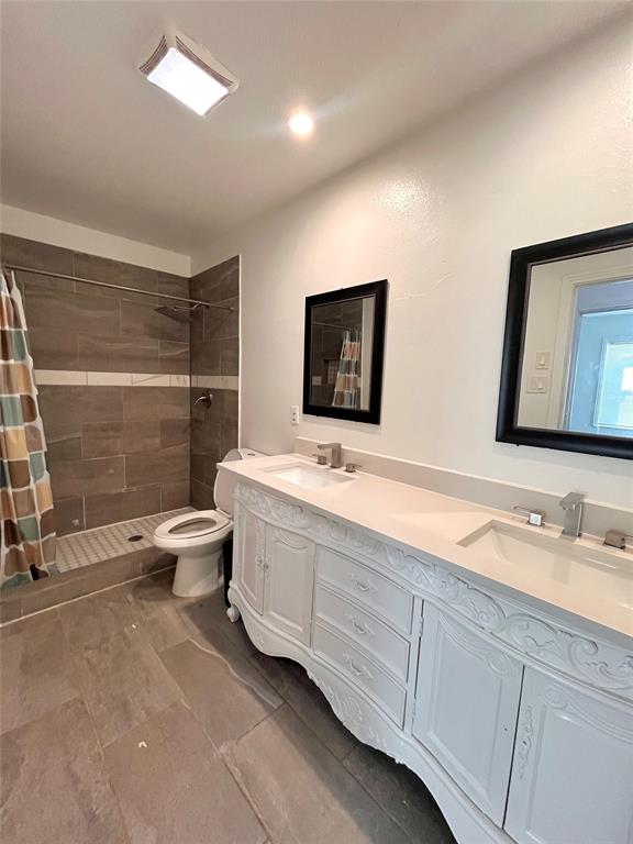 1324 Maple Drive Garland, TX 75040 - Photo 6 of 10 a bathroom with a double vanity sink a toilet and mirror