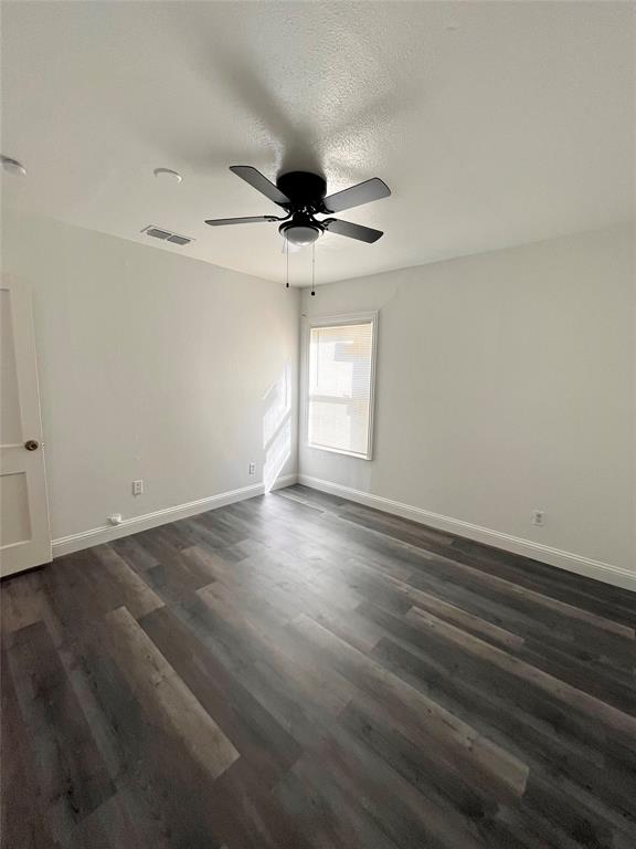 1324 Maple Drive Garland, TX 75040 - Photo 7 of 10 an empty room with wooden floor ceiling fan and windows